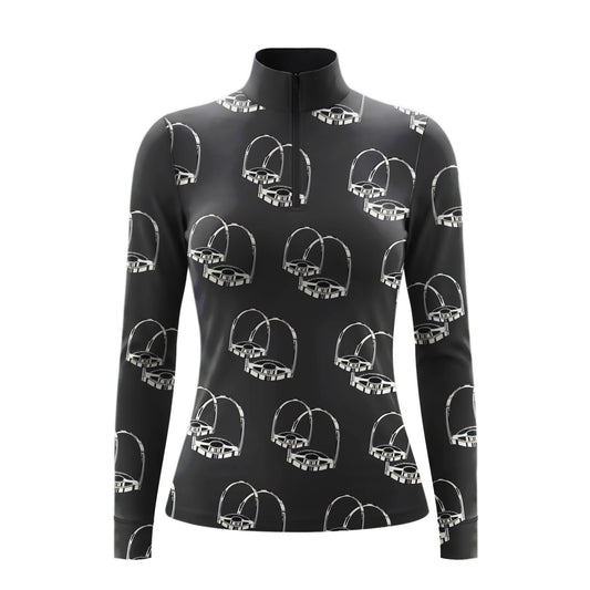 Model standing beside brown horse’s head wearing monochrome sketch stirrup hardware long sleeve riding top against light grey stable wall