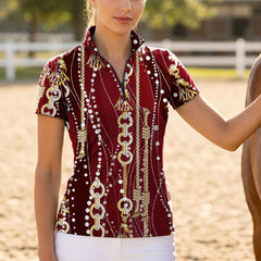 Model wearing chain and rope print riding top beside a horse at sunlit dirt arena