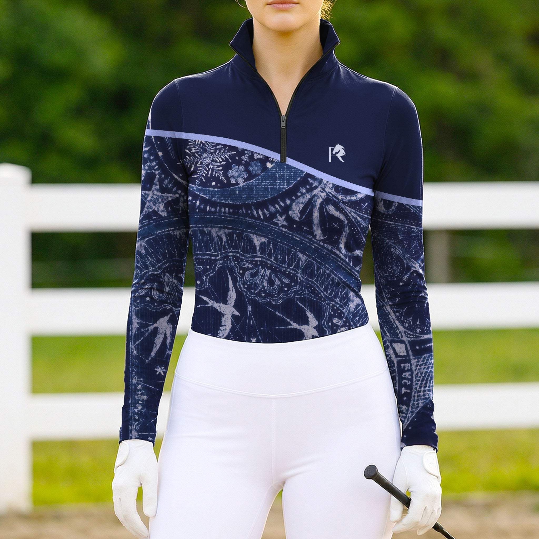 Model wearing the Celestial Night Print Color-Block Riding Top at an outdoor equestrian arena, with jumps in the background