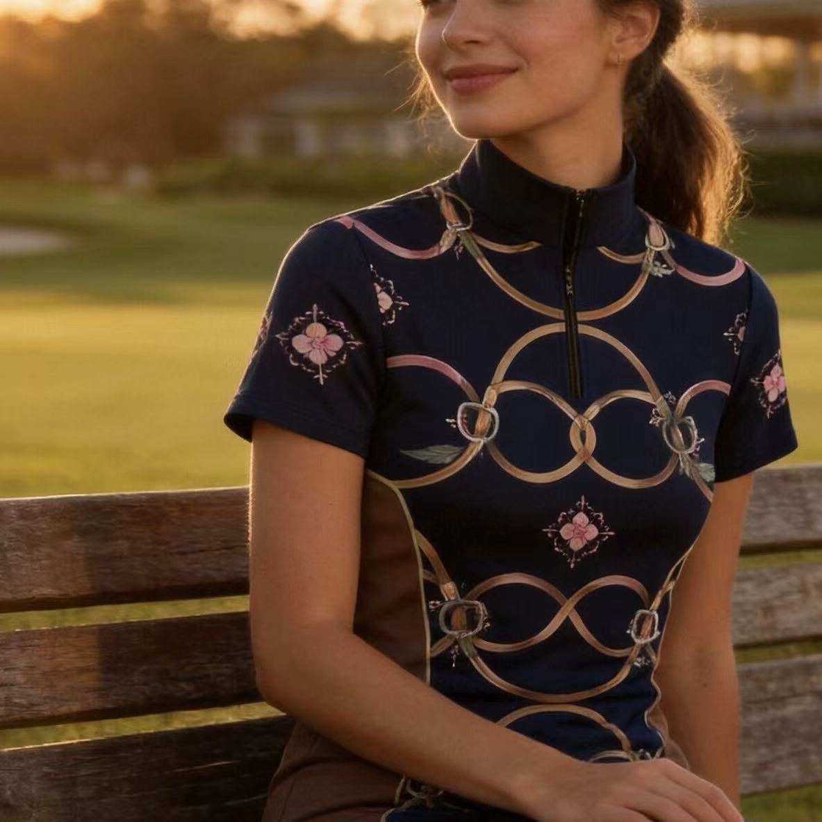 Model wearing navy floral riding top seated on a bench at sunset