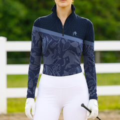 Person wearing a navy equestrian top with horse pattern and white pants in an outdoor setting.