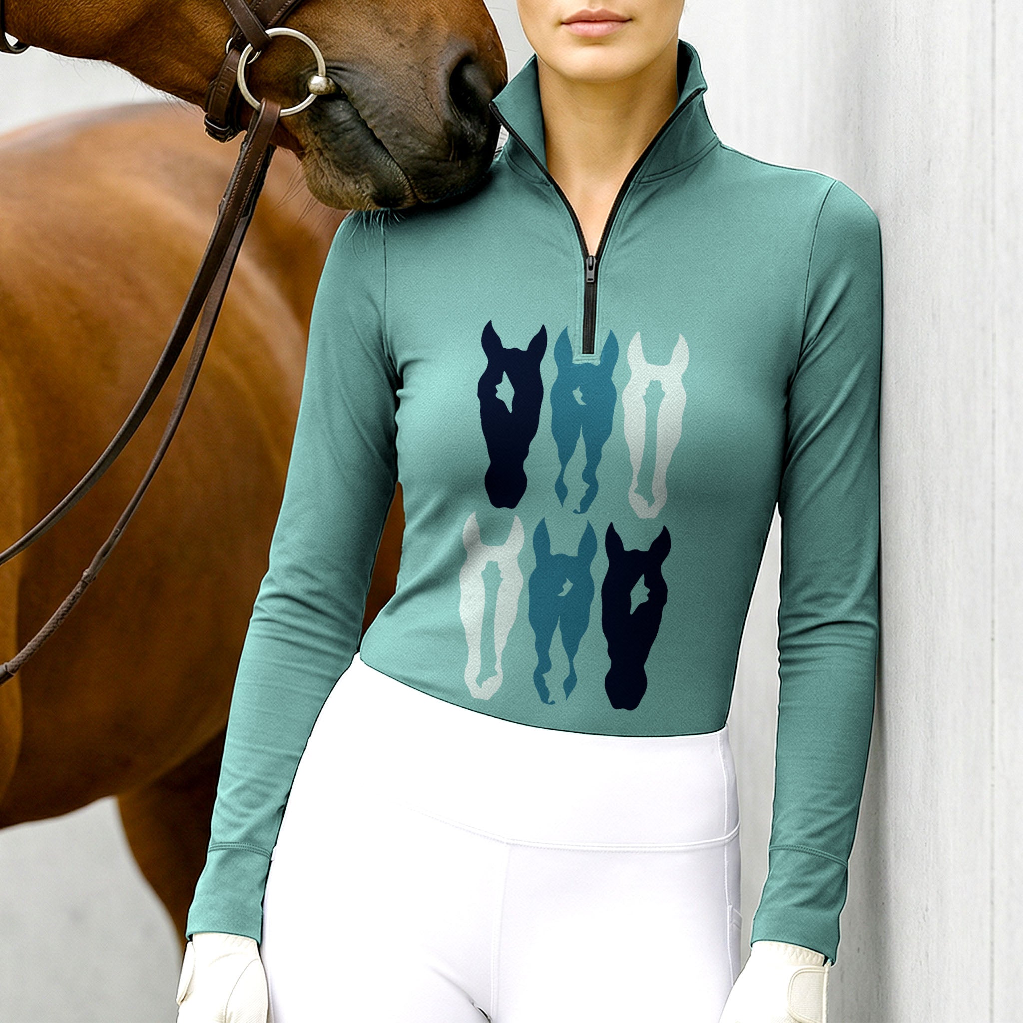 Woman wearing RIDER ATELIER teal stacked horse silhouette quarter-zip top at the outdoor pasture