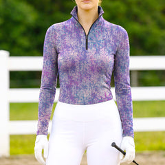 Woman wearing RIDER ATELIER tie-dye snaffle bit lavender purple quarter-zip top at the outdoor pasture