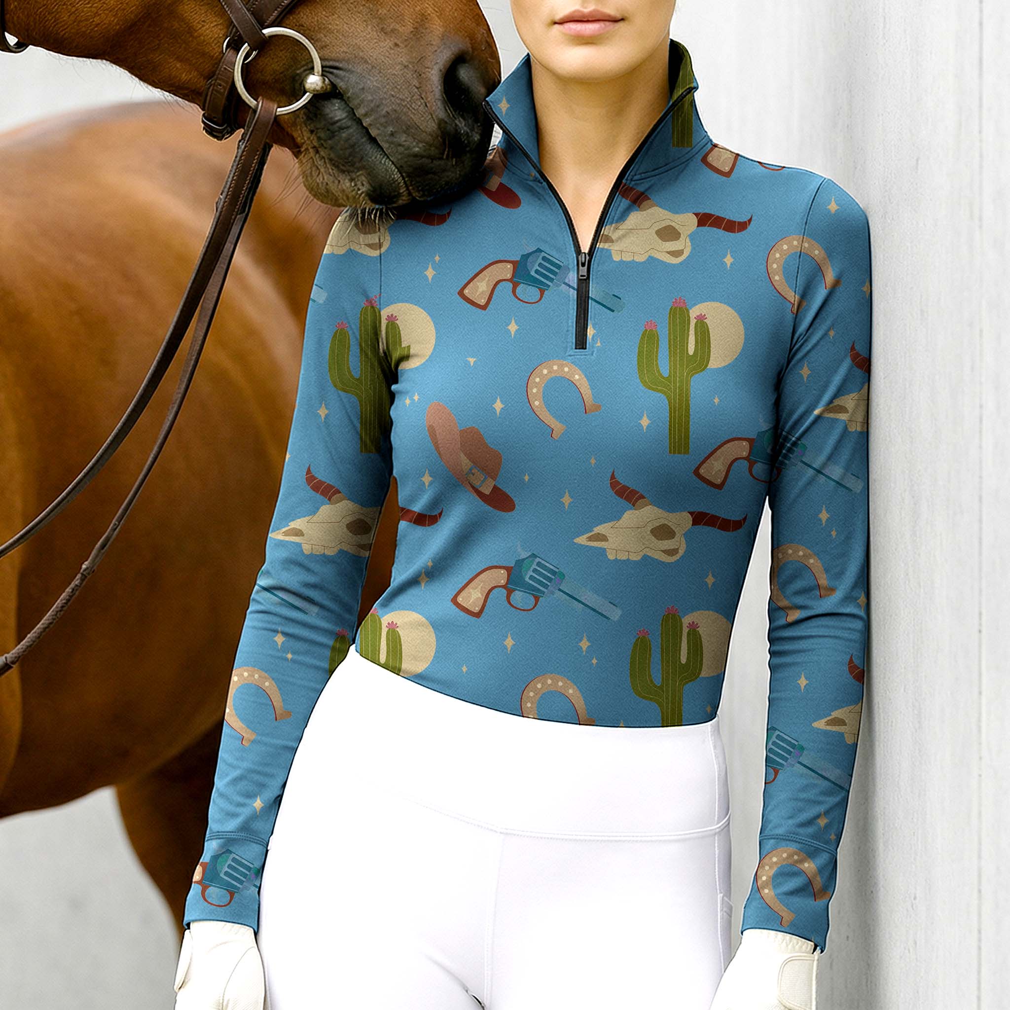 Model wearing the RIDER ATELIER Western Cowboy Print Riding Top at the stable, with a chestnut horse, highlighting the print’s playful details