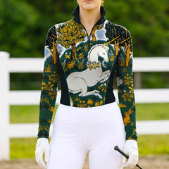 Model wearing whimsical forest print riding top at sunlit dirt equestrian arena