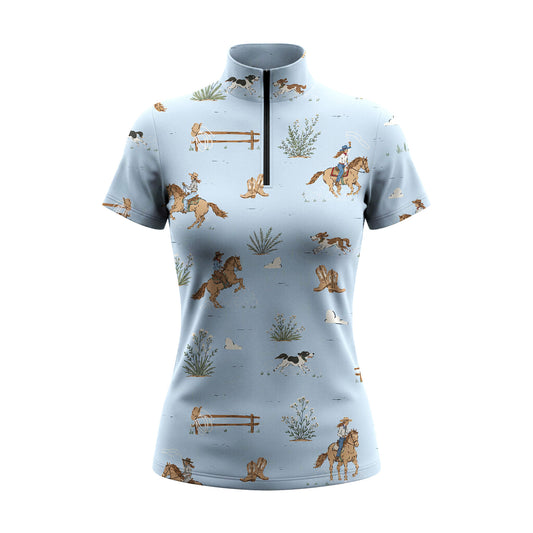 White background studio product shot of pale light blue short sleeve quarter-zip riding top with scattered cowboy horse hound western ranch print