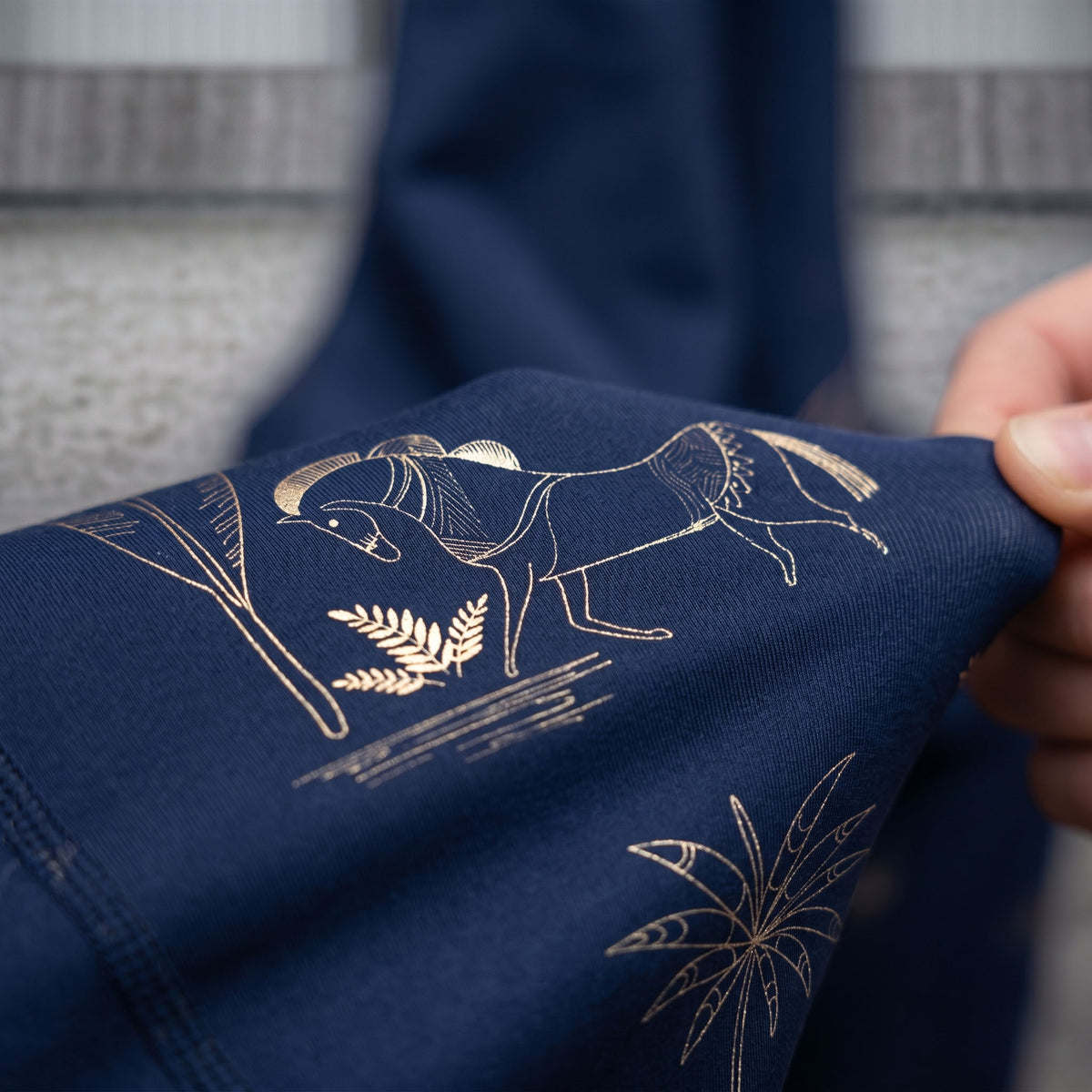 Close-up of an original gold horse and botanical print on navy fabric