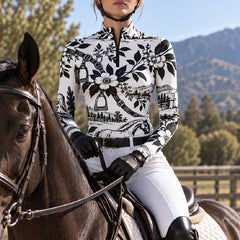 Rider wearing the printed riding top seated on a dark brown horse in a mountain pasture setting