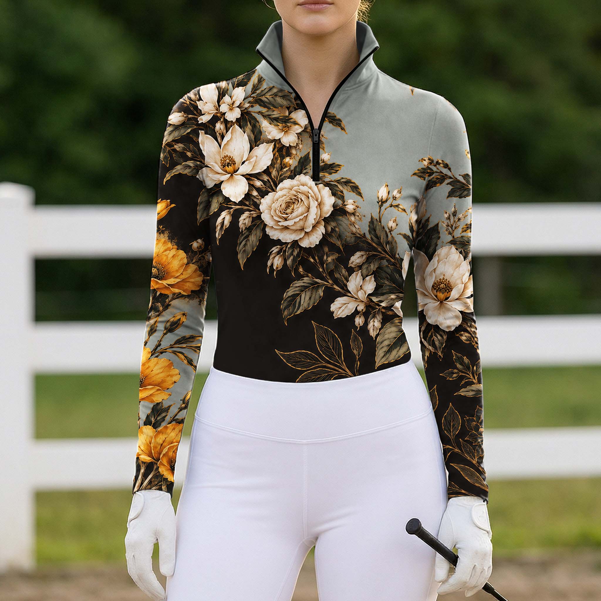 Rider wearing the floral riding top, white breeches and riding gloves holding a crop in front of a white arena fence