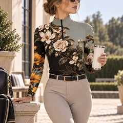 Standing rider wearing the floral riding top holding an insulated tumbler, leaning on a stone barn pillar