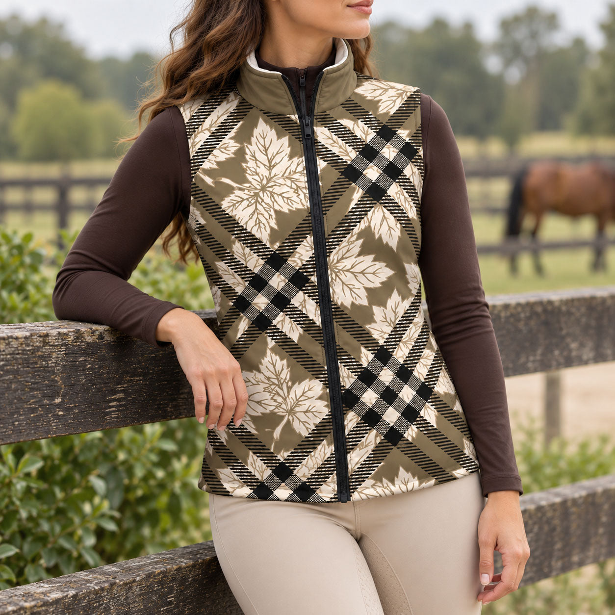 Olive toned maple leaf and plaid print side of reversible vest with solid stand up collar, worn over a brown quarter zip top with beige riding breeches and tall boots