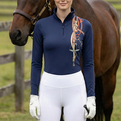 Woman wearing navy equestrian tack bouquet print long sleeve zip top standing beside a chestnut horse at the stable