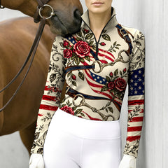 Woman wearing the cream printed riding top with white breeches while holding a brown horse by leather reins