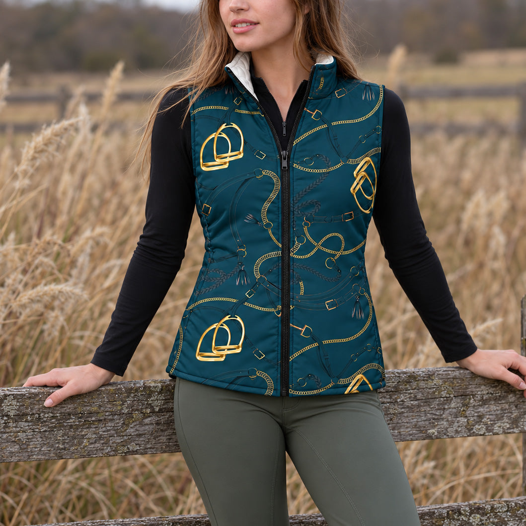 Deep teal reversible quilted equestrian vest with gold stirrup and chain print worn near a wooden fence
