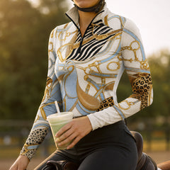 Stable doorway lifestyle shot, female equestrian beside brown horse, dressed in cream equestrian tack zebra leopard print riding top, white breeches and white riding gloves