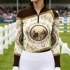 Outdoor equestrian show arena front‑view lifestyle shot of female rider with hands on hips, wearing cream‑black ink‑wash floral long‑sleeve riding top and white riding breeches