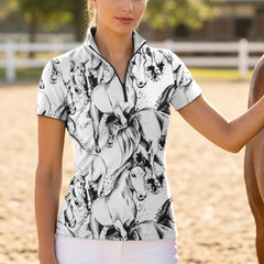 Outdoor green pasture side‑view lifestyle shot of female equestrian leaning on white wooden fence wearing white short‑sleeve quarter‑zip riding top with black sketch galloping horse artwork