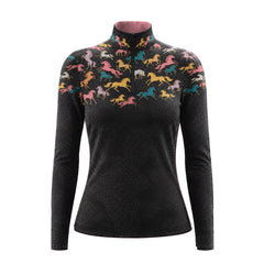 Stable doorway portrait of female rider in black colorful galloping horse silhouette print riding top, leaning against wooden saddle stand paired with white breeches