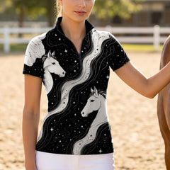 Outdoor paddock white‑fence front‑view lifestyle shot of female rider beside brown horse wearing black celestial dual‑horse floral shoulder print short‑sleeve riding top paired with white breeches