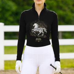 Model wearing the 2026 Year of the Horse Long-Sleeve Riding Top at an outdoor equestrian arena, with a white fence
