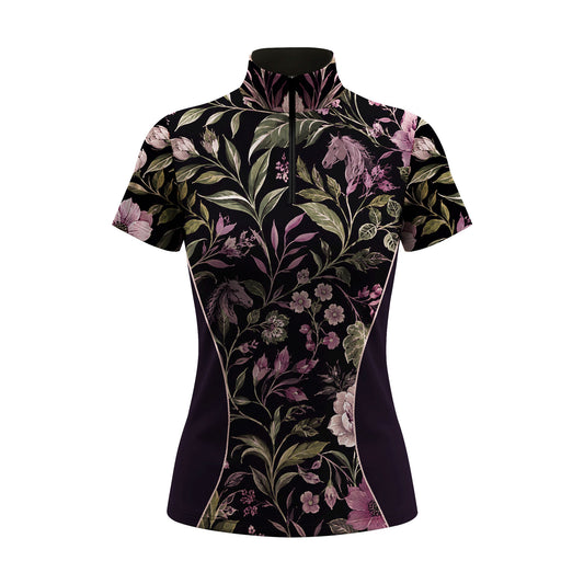 Show‑jumping arena outdoor shot of female equestrian in black short‑sleeve quarter‑zip riding top with purple floral horse silhouette print, wearing white riding gloves and white breeches