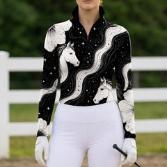Outdoor barn lifestyle portrait of female equestrian in black star galaxy horse floral pattern long‑sleeve quarter‑zip riding top