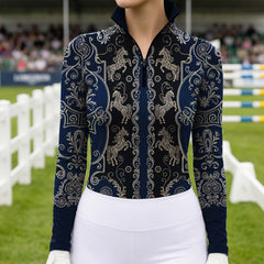 Lifestyle shot with brown horse nuzzling rider’s shoulder, female equestrian leans against light wall in navy‑black vintage golden carousel‑horse scroll‑filigree print riding top and white riding gloves