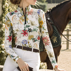 Clean white background studio product mockup of cream long‑sleeve quarter‑zip riding top with exclusive watercolor wildflower and white unicorn‑pony all‑over print