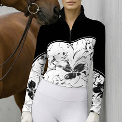 Outdoor wall‑side lifestyle shot with brown horse nuzzling rider’s shoulder, model wearing black‑white ink‑wash floral long‑sleeve riding top and white riding breeches