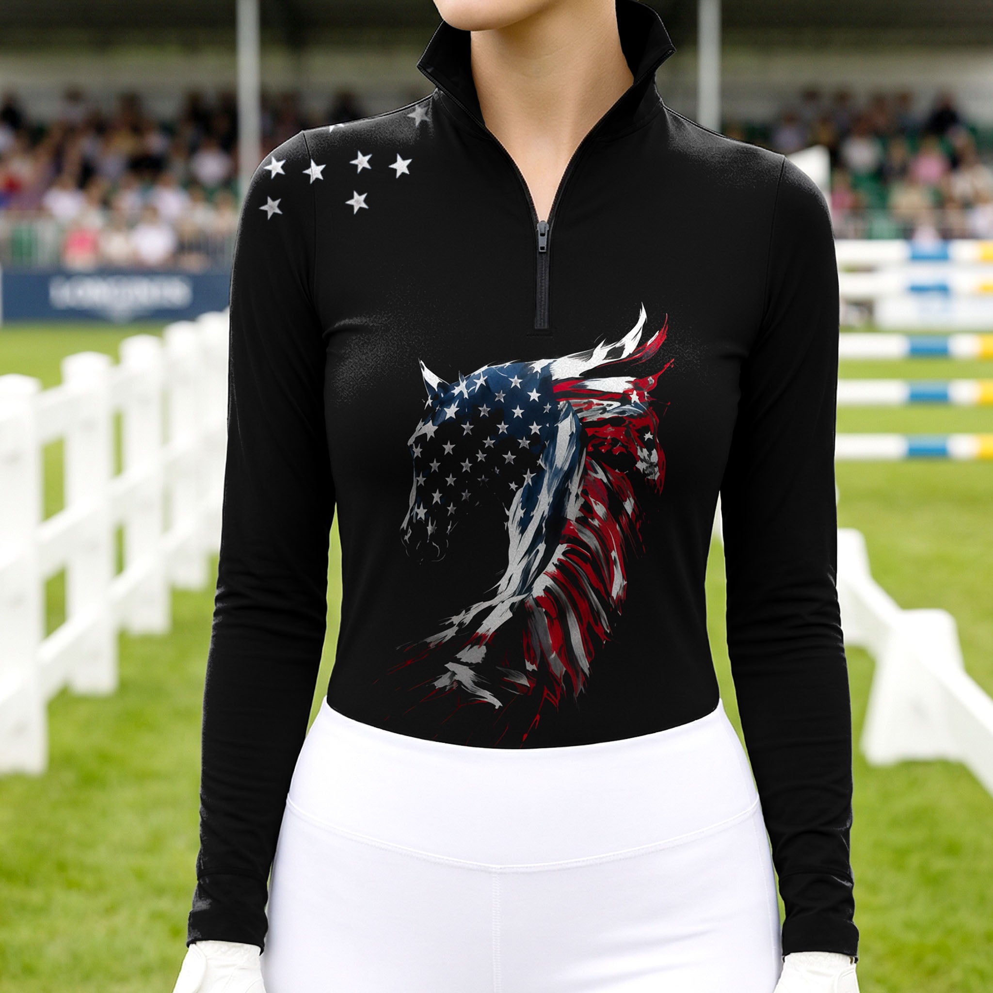 Model wearing the American Flag Horse Head Print Riding Top at a competition arena, with jumps in the background
