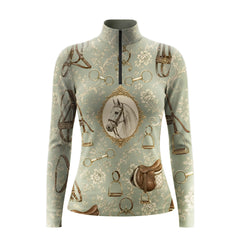 White background studio shot of muted sage green antique tack and framed horse portrait long sleeve quarter zip riding top