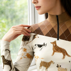 Close-up detail shot of the brown argyle plaid shoulder panel and border collie sketch dog print on the cream riding top
