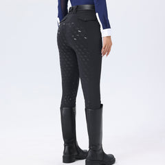 Person wearing black riding pants with horse pattern and black riding boots on a white background