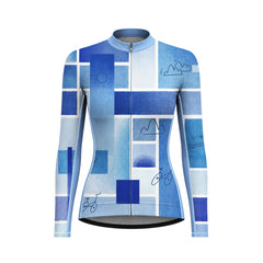 Female model wearing blue grid landscape line art long sleeve bike jersey riding along coastal seaside road at sunset, front torso partial view
