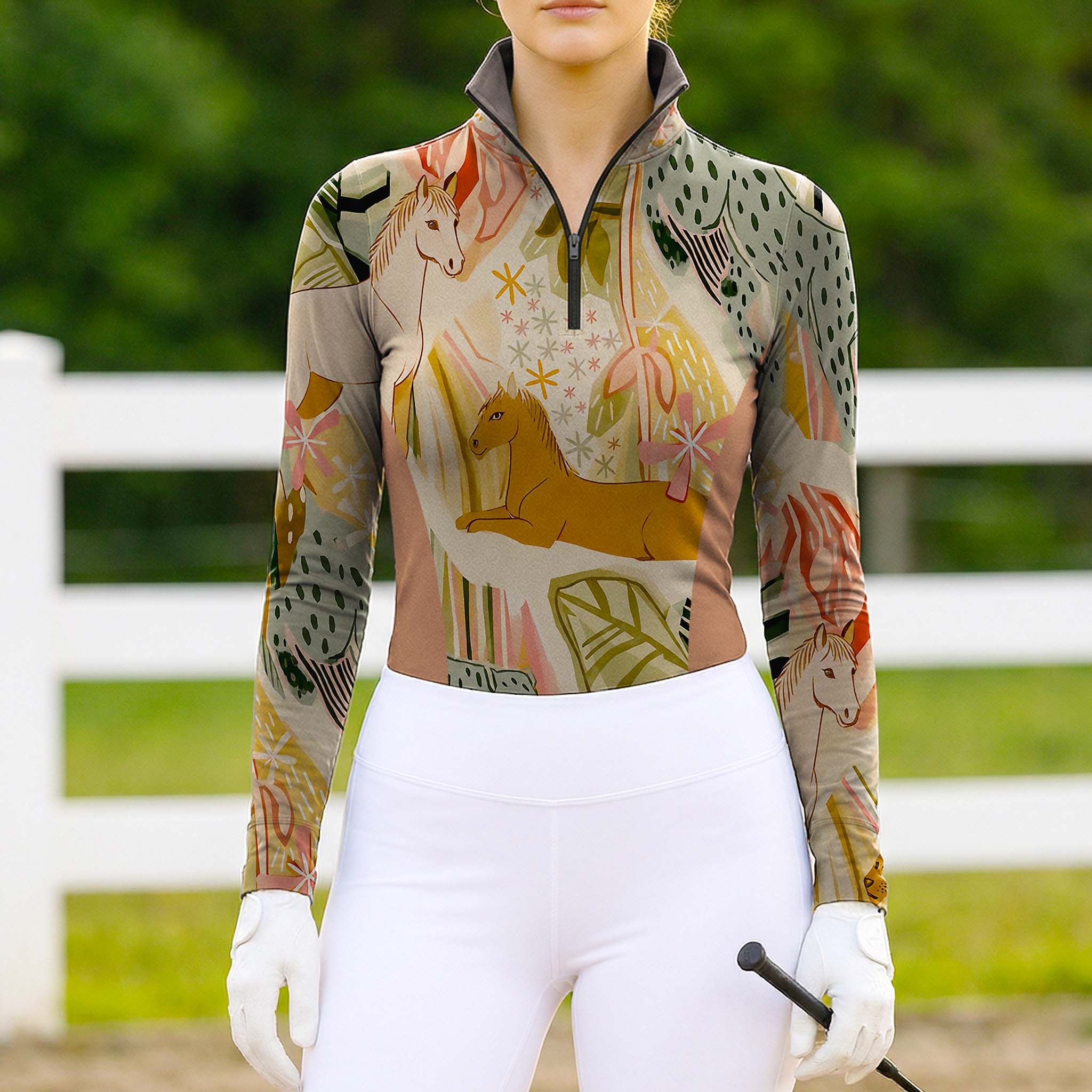 Model wearing bohemian equestrian print riding top at sunlit dirt equestrian arena