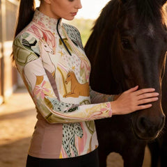 Model wearing whimsical equestrian print riding top touching a dark horse inside the stable