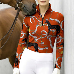 Full-body model shot wearing upscale heritage equestrian hardware long sleeve top at sunlit green pasture white wooden fence, holding riding crop
