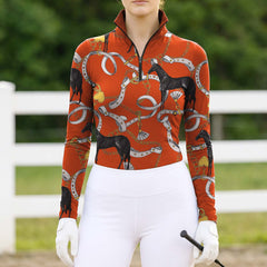 White background studio shot of burnt terracotta orange luxury equestrian leather bit gold chain black horse allover print long sleeve quarter zip riding top
