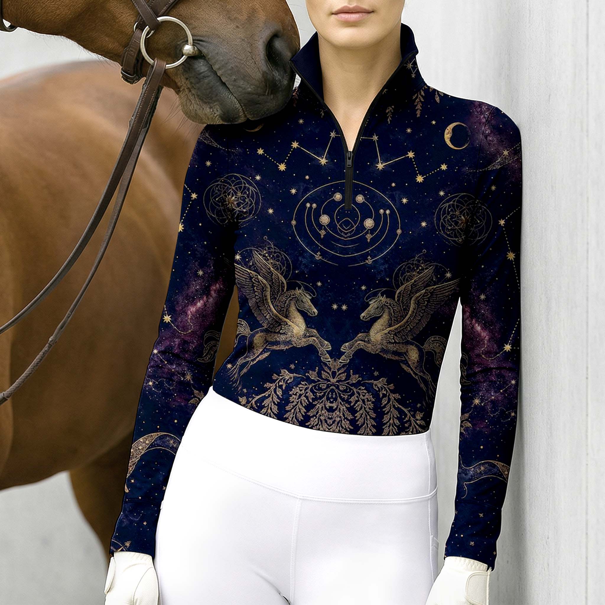 Outdoor wall lifestyle shot of female rider beside horse wearing midnight navy golden pegasus celestial‑print long‑sleeve riding top