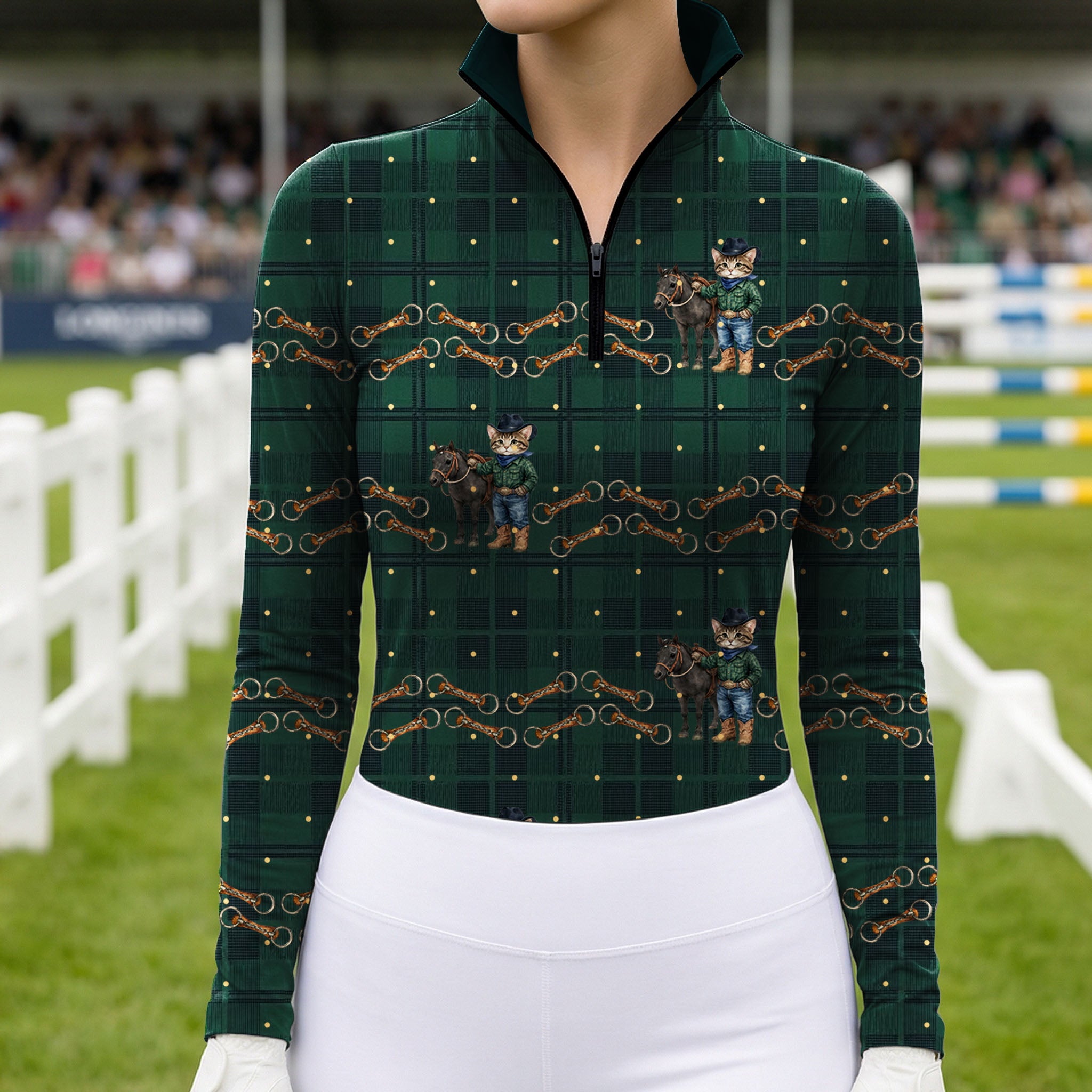Showground arena model shot of rider in dark green tartan quarter‑zip long‑sleeve riding top featuring playful cowboy cat‑pony horse‑bit print