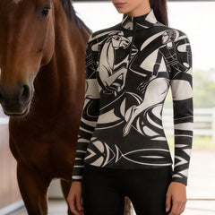 Model standing beside a chestnut horse inside light stable wearing black white cubist rider horse print long sleeve riding top