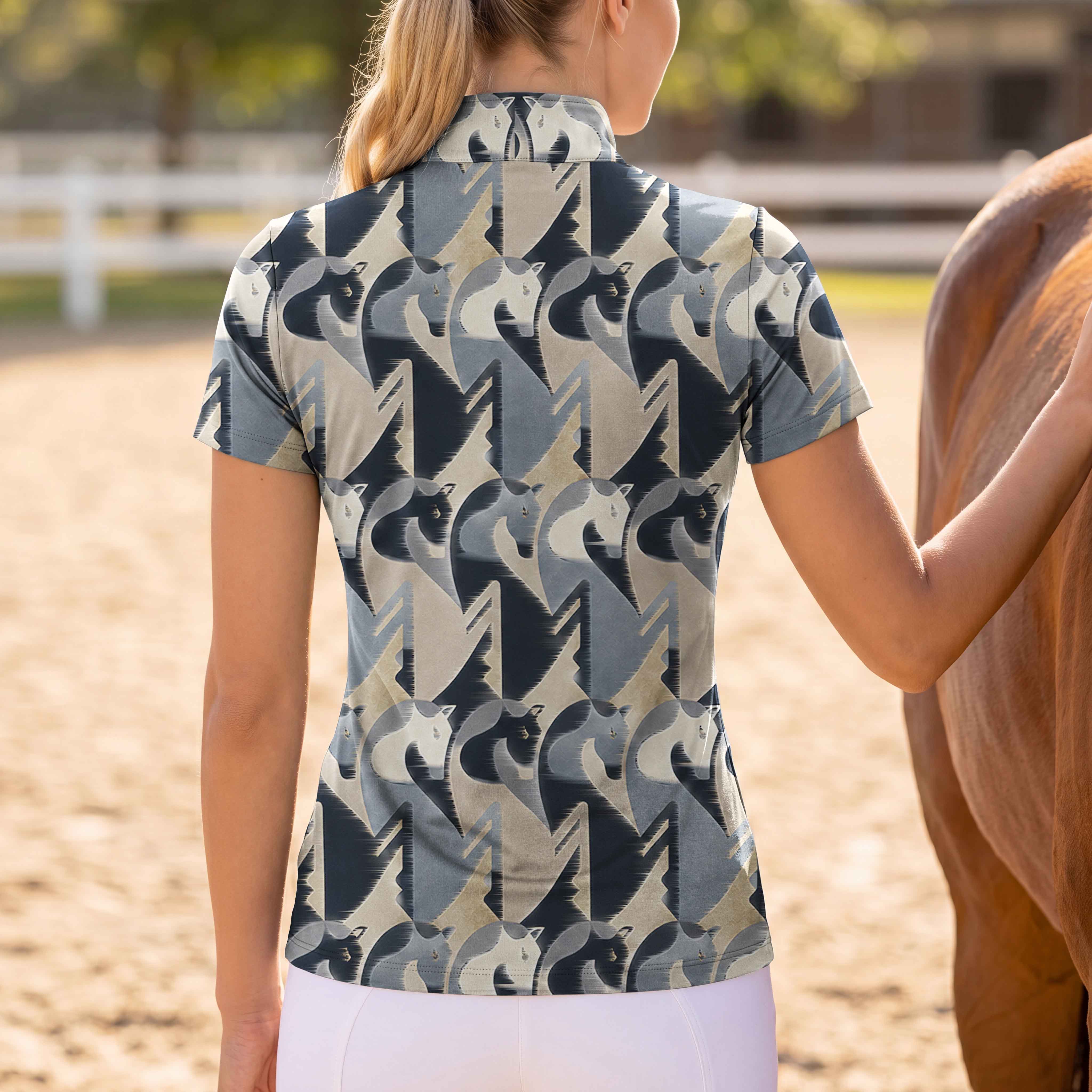 Bright sunlit stable yard shot of female rider viewed from the back standing beside brown horse wearing charcoal sand abstract geometric horse head all-over print short sleeve quarter-zip riding top paired with white riding leggings