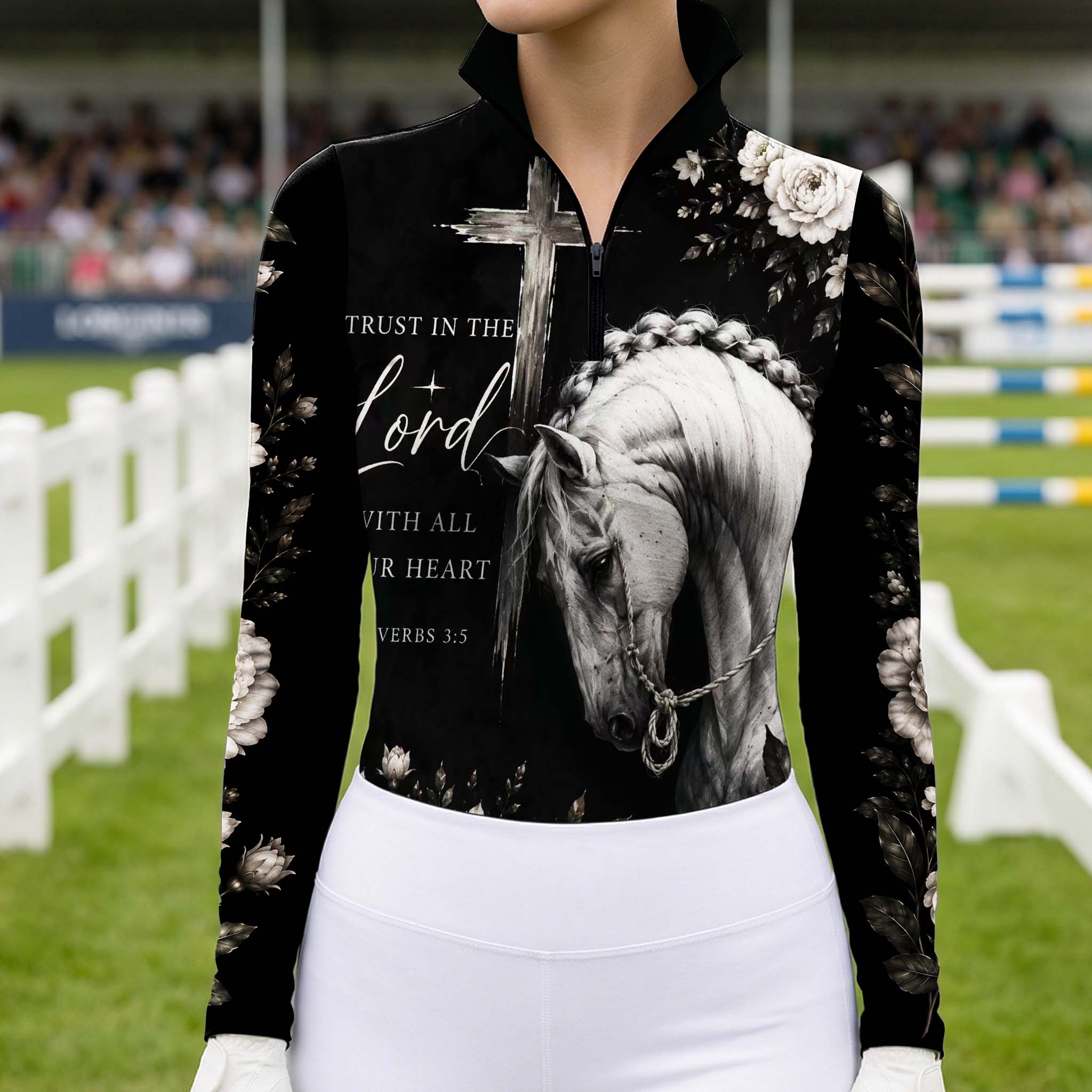 Model wearing spiritual dark floral horse cross riding top at outdoor equestrian show jumping arena with spectator stands
