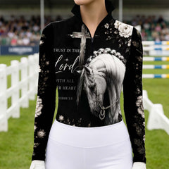 Model wearing spiritual dark floral horse cross riding top at outdoor equestrian show jumping arena with spectator stands
