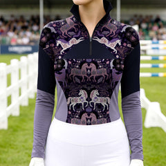 Model wearing dark purple folk floral horse two-tone raglan riding top at outdoor equestrian show jumping arena with spectator stands
