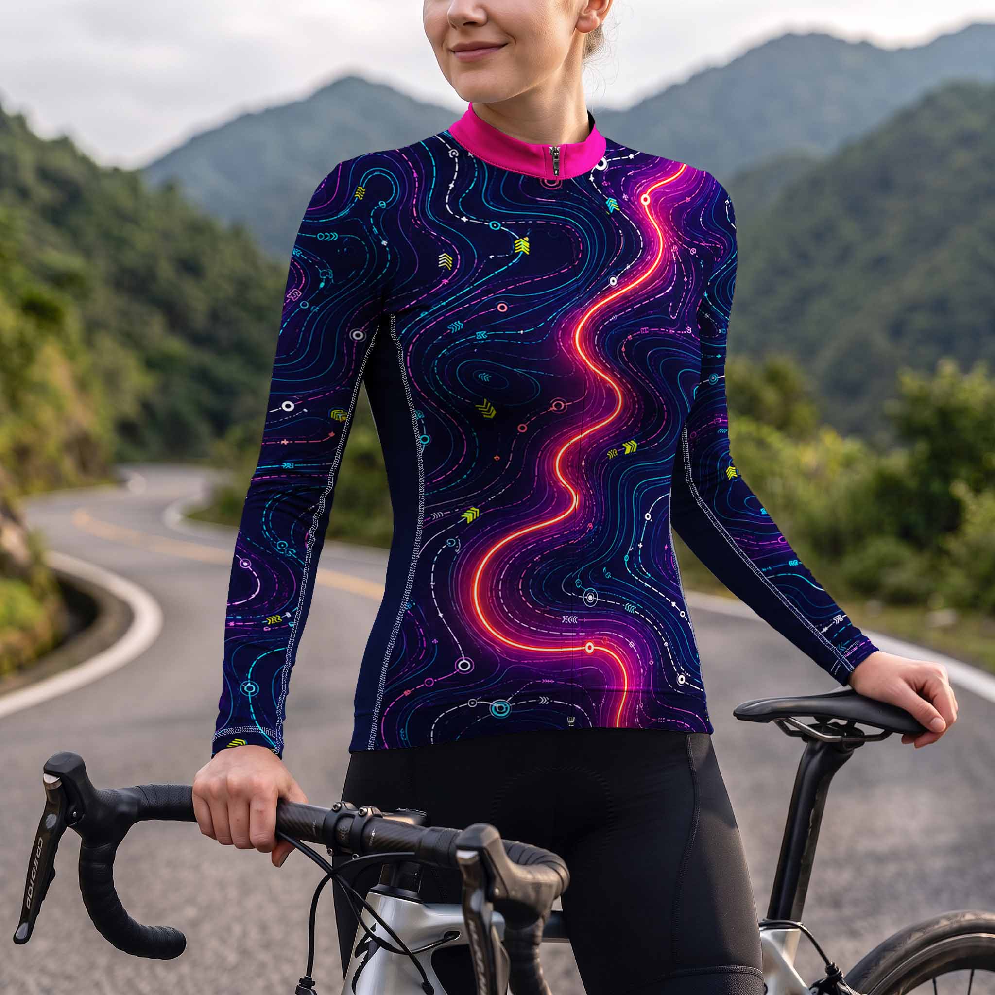 Female model wearing dark navy neon glow circuit streamline long sleeve bike jersey riding road bike on winding mountain trail, front torso view
