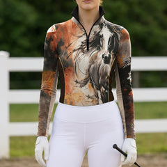 Outdoor riding arena full model shot of rider in artistic stallion watercolor‑print long‑sleeve riding top with white breeches and riding gloves