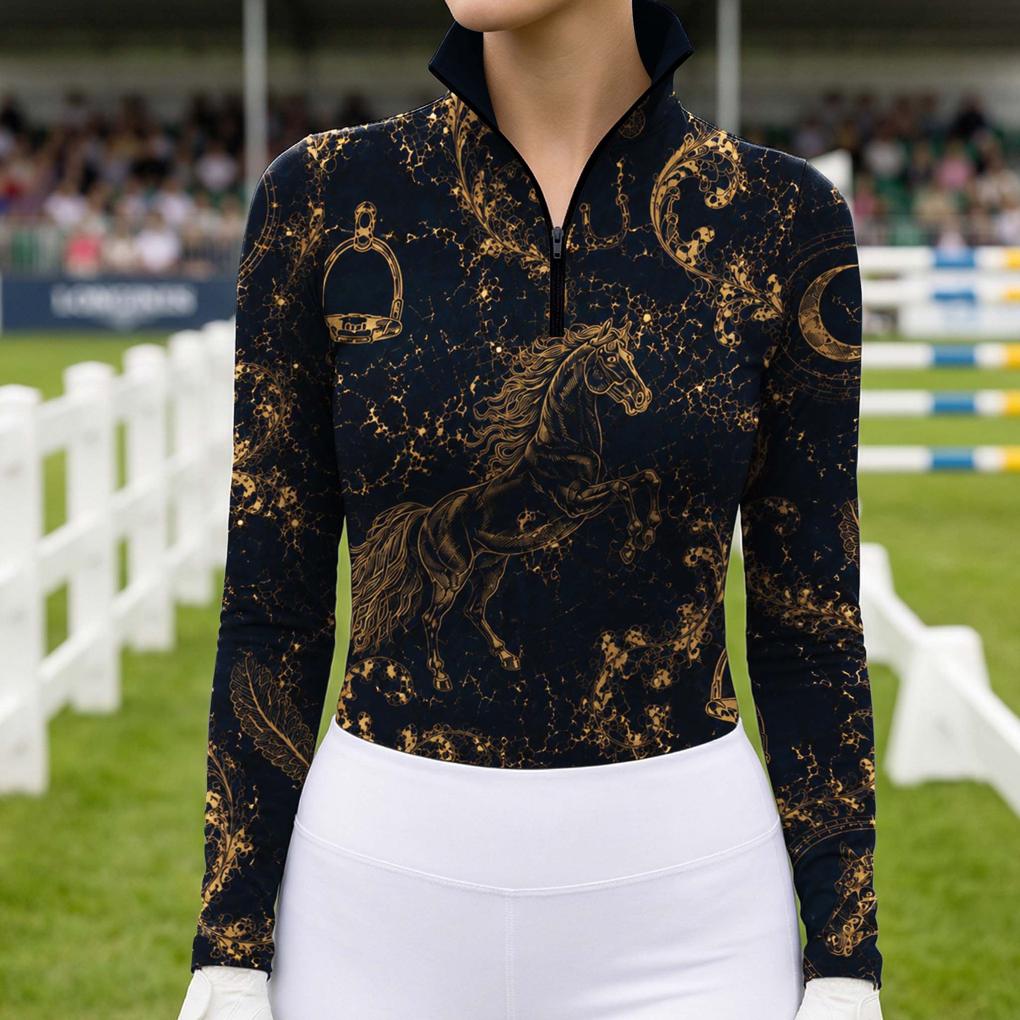 Full-body model portrait holding a riding crop at a spectator-filled outdoor equestrian jumping arena displaying the opulent gold celestial horse print riding top
