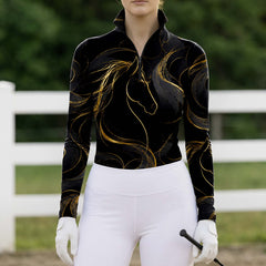 Model wearing sleek black gold horse riding top at sunlit green pasture white fence