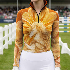 Bright outdoor equestrian show arena shot of model wearing golden sunburst unicorn art print long sleeve quarter-zip riding top with white riding breeches